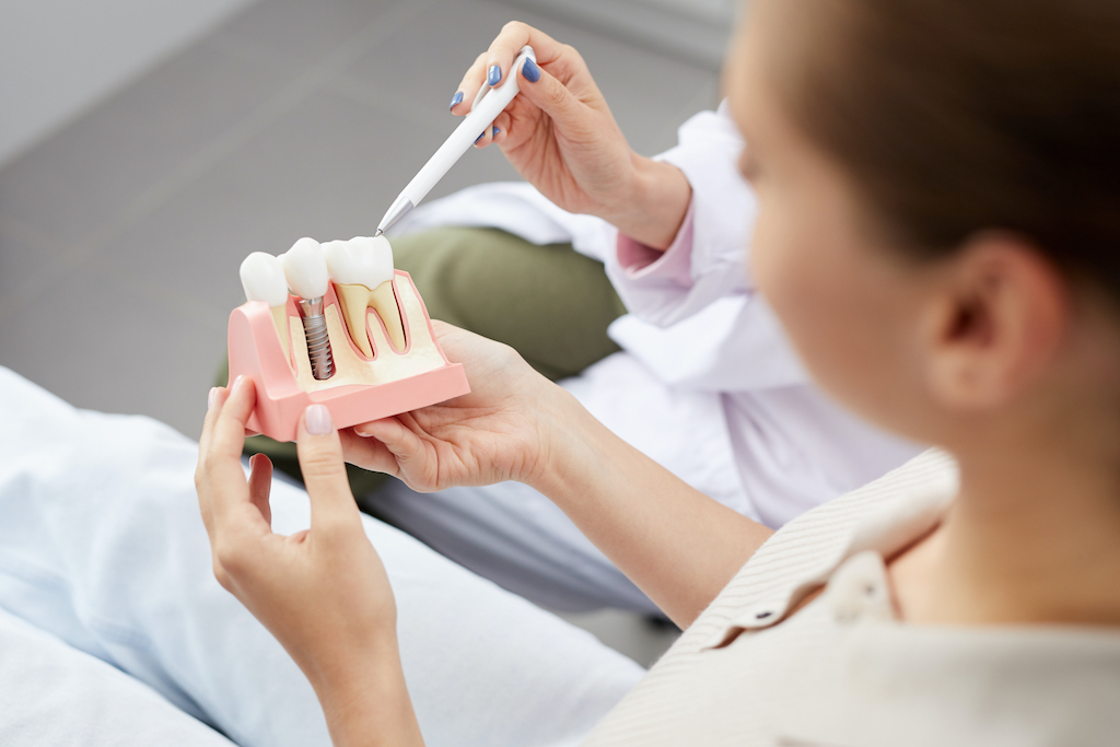 a patient of oral surgery looking at an example of a dental implant