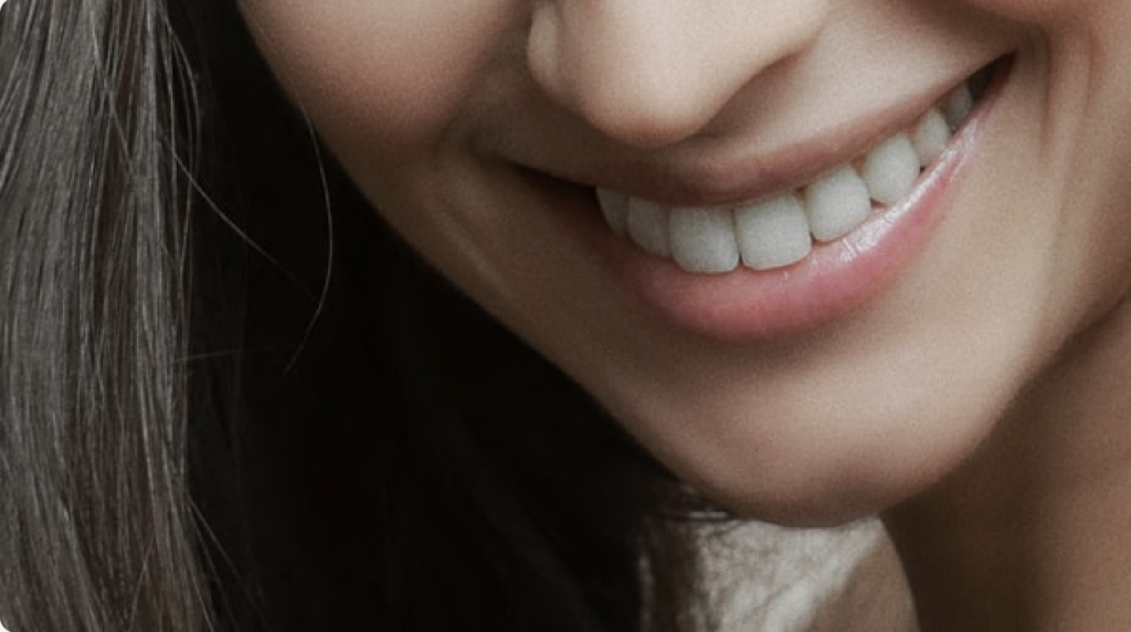 a woman smiling after her oral surgery procedure such as a dental implant, dentures, or tooth extraction